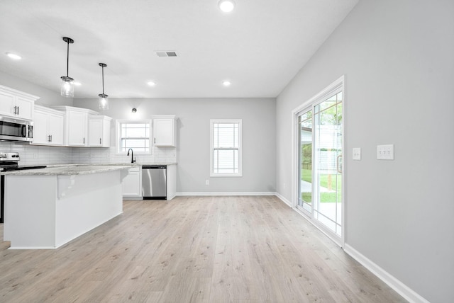 kitchen featuring appliances with stainless steel finishes, a kitchen island, white cabinetry, and pendant lighting