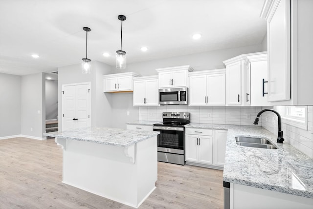 kitchen featuring appliances with stainless steel finishes, sink, white cabinets, a kitchen island, and hanging light fixtures