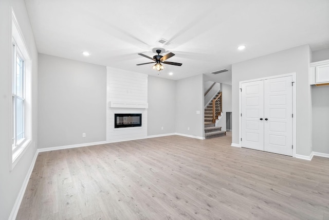 unfurnished living room featuring a fireplace, light hardwood / wood-style floors, plenty of natural light, and ceiling fan