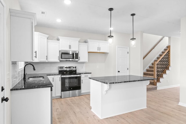 kitchen with white cabinets, decorative light fixtures, sink, and stainless steel appliances