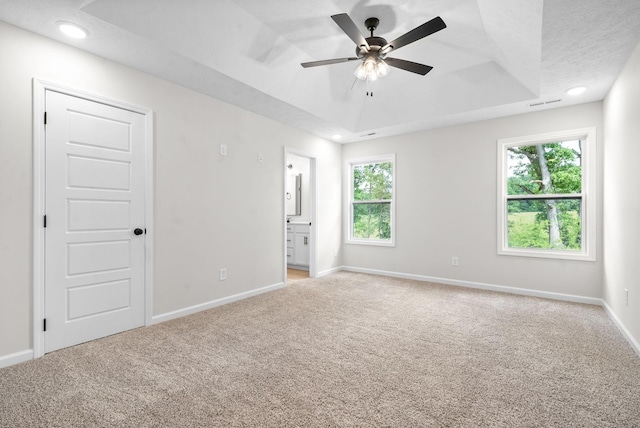 carpeted empty room featuring a tray ceiling, ceiling fan, and a textured ceiling