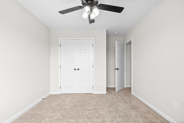 unfurnished bedroom featuring light carpet, a closet, and ceiling fan