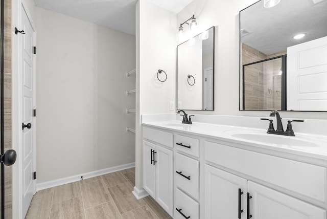 bathroom with vanity, a shower with shower door, and a textured ceiling