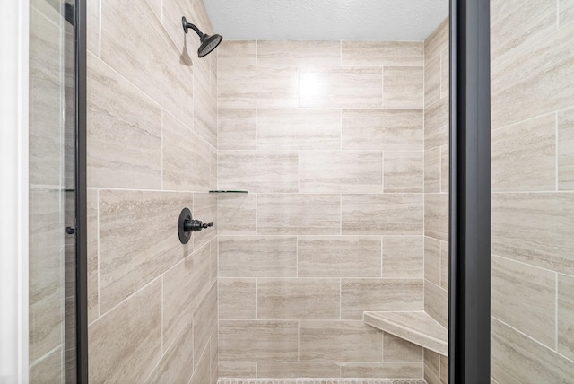 bathroom featuring a tile shower and a textured ceiling