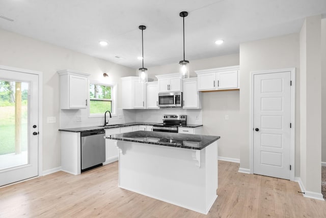 kitchen featuring appliances with stainless steel finishes, tasteful backsplash, white cabinets, a kitchen island, and hanging light fixtures