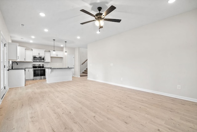 unfurnished living room with ceiling fan, sink, and light hardwood / wood-style flooring