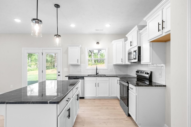 kitchen featuring stainless steel appliances, white cabinetry, a kitchen island, and sink