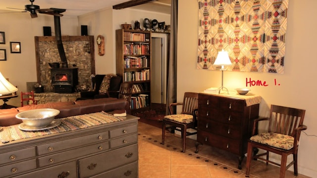 sitting room featuring light tile patterned floors, a wood stove, and ceiling fan