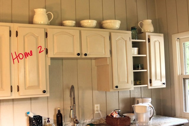 kitchen featuring white cabinetry and wooden walls