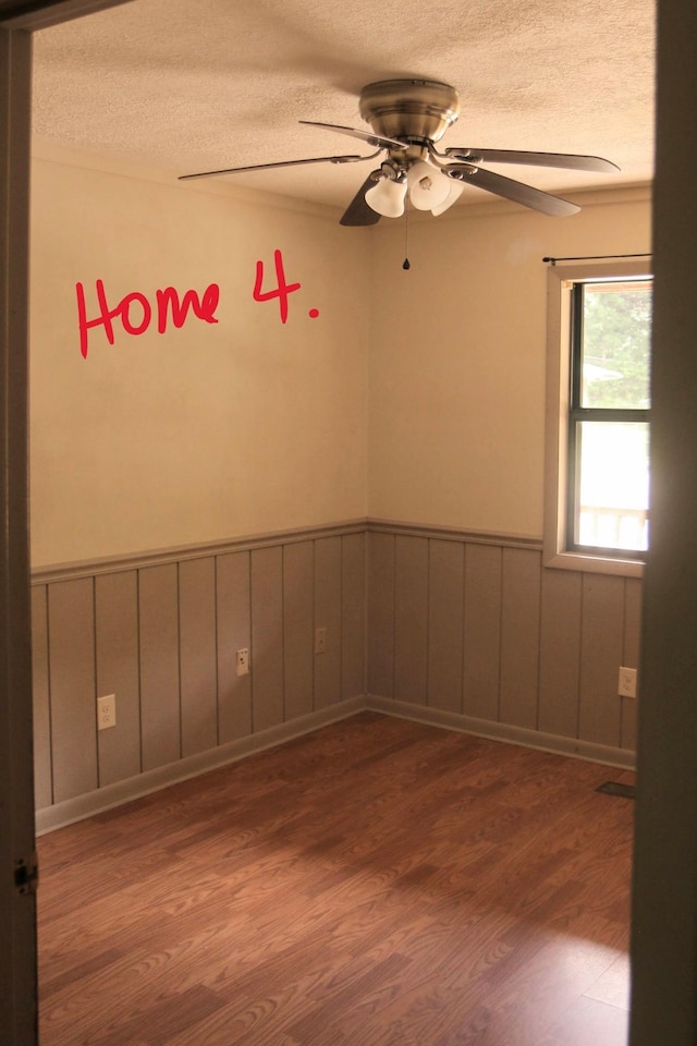 empty room featuring a textured ceiling, dark hardwood / wood-style flooring, and ceiling fan