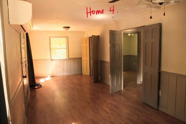 unfurnished bedroom featuring an AC wall unit, ceiling fan, and dark hardwood / wood-style floors