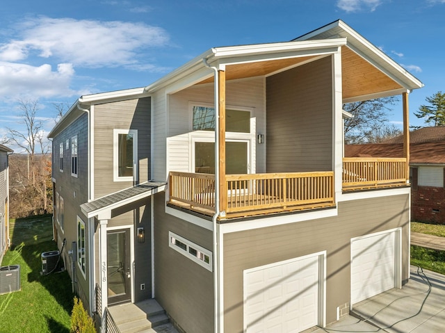 view of front of property featuring a garage, a balcony, and central air condition unit