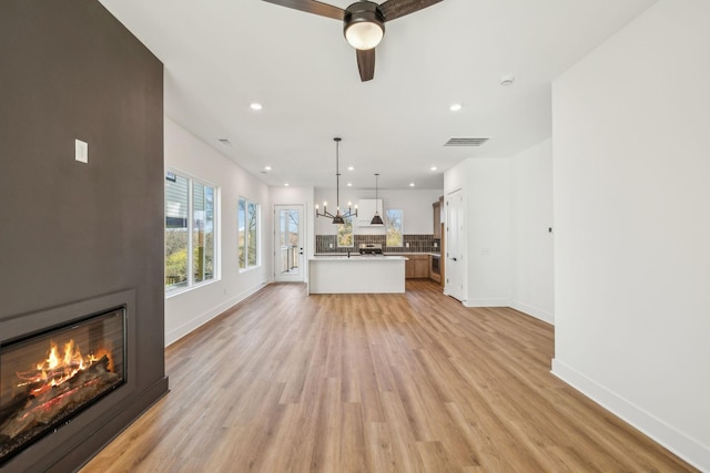 unfurnished living room with a large fireplace, light hardwood / wood-style flooring, and ceiling fan