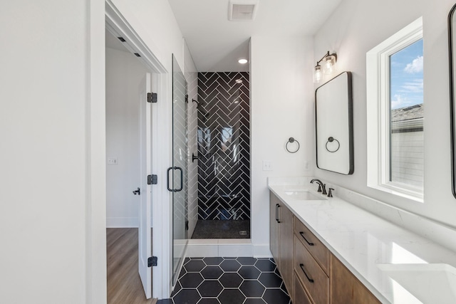 bathroom with tile patterned floors, a shower with door, and vanity