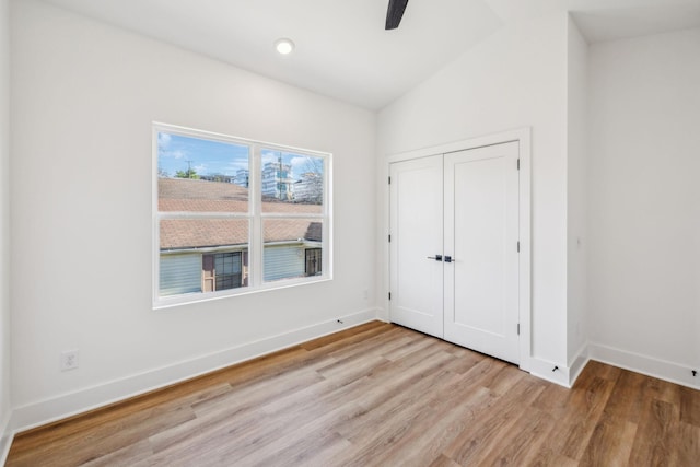 unfurnished bedroom with ceiling fan, vaulted ceiling, light wood-type flooring, and a closet