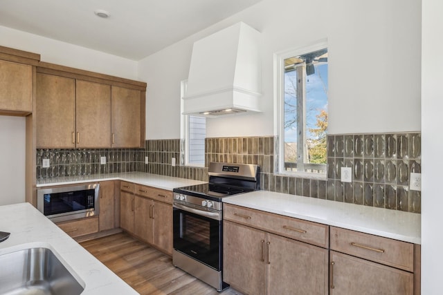 kitchen featuring premium range hood, a wealth of natural light, tasteful backsplash, and stainless steel appliances