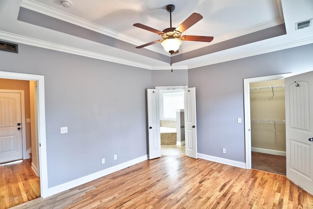 unfurnished bedroom with light hardwood / wood-style flooring, a raised ceiling, ceiling fan, and crown molding