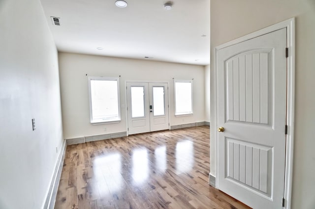 foyer entrance with plenty of natural light, french doors, and light hardwood / wood-style flooring