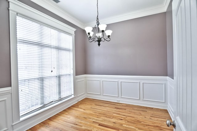 unfurnished room featuring a healthy amount of sunlight, crown molding, and a chandelier