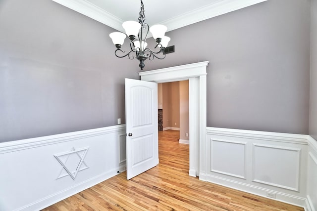 spare room with crown molding, a chandelier, and light wood-type flooring