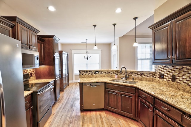 kitchen with pendant lighting, sink, light wood-type flooring, appliances with stainless steel finishes, and tasteful backsplash