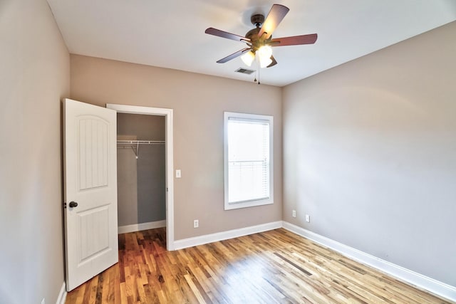 unfurnished bedroom with ceiling fan, a closet, and hardwood / wood-style floors