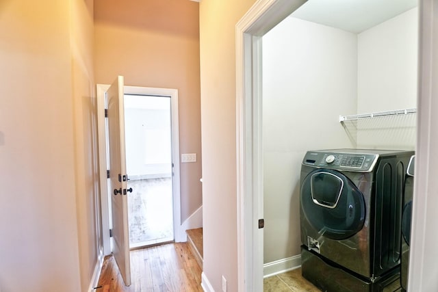 laundry area with washer / dryer and light wood-type flooring