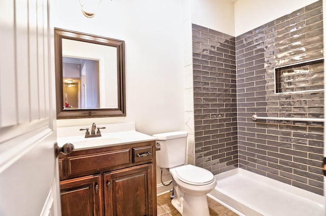 bathroom with tile patterned floors, vanity, toilet, and a tile shower