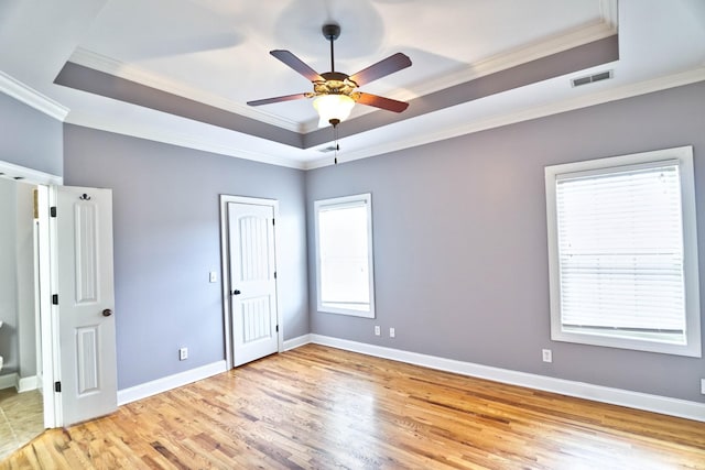 unfurnished room featuring ceiling fan, a raised ceiling, ornamental molding, and light hardwood / wood-style flooring