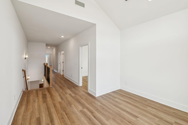 empty room with light hardwood / wood-style floors and lofted ceiling