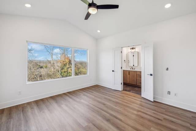 unfurnished bedroom featuring connected bathroom, ceiling fan, light hardwood / wood-style flooring, and lofted ceiling