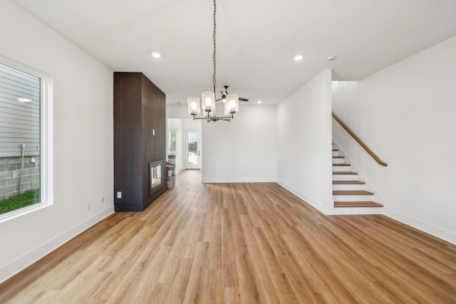 unfurnished living room featuring a chandelier and light hardwood / wood-style flooring