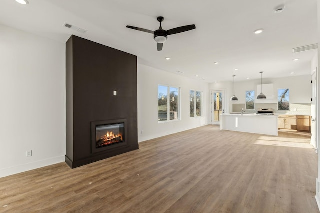 unfurnished living room featuring ceiling fan, a fireplace, and light hardwood / wood-style flooring