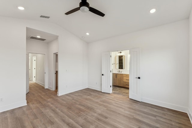 unfurnished bedroom featuring lofted ceiling, sink, ensuite bath, ceiling fan, and light hardwood / wood-style floors