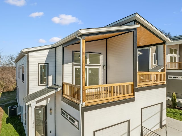 view of side of property featuring a balcony, a garage, and central AC unit