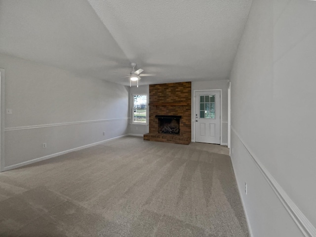 unfurnished living room with a fireplace, a textured ceiling, light colored carpet, and ceiling fan