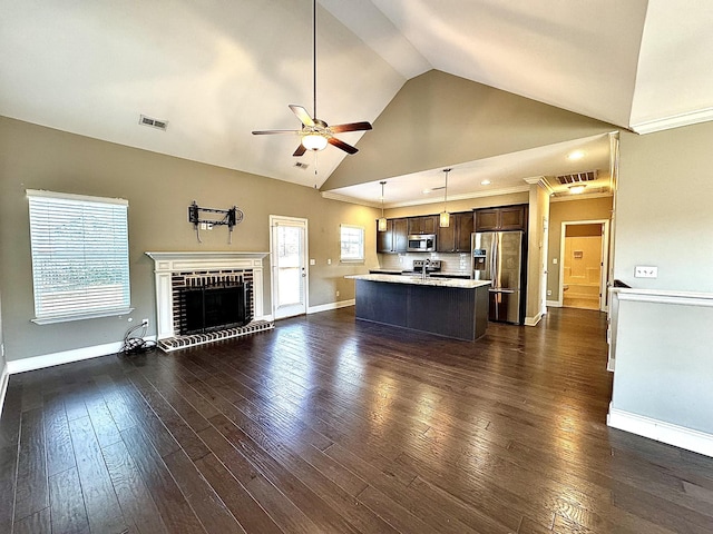 unfurnished living room featuring a wealth of natural light, a fireplace, ceiling fan, and dark wood-type flooring