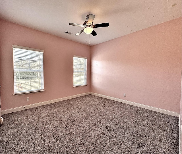 spare room with ceiling fan and dark colored carpet