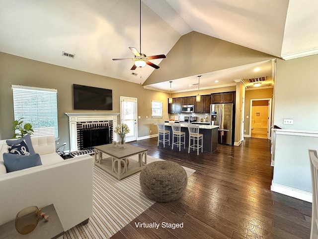 living room featuring a wealth of natural light, dark wood-type flooring, lofted ceiling, and a brick fireplace