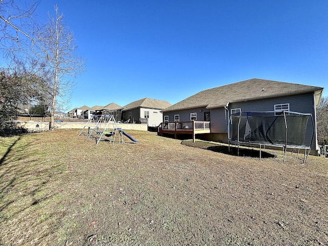 view of yard with a trampoline, a deck, and a playground