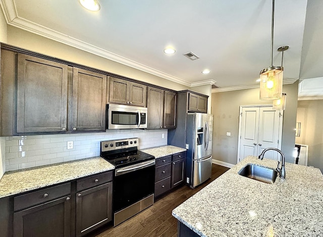 kitchen with light stone countertops, sink, hanging light fixtures, decorative backsplash, and appliances with stainless steel finishes