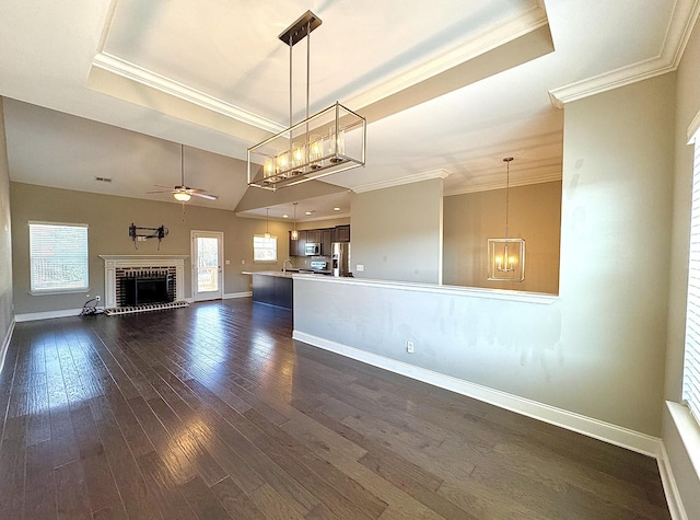 unfurnished living room featuring a raised ceiling, vaulted ceiling, ceiling fan, dark hardwood / wood-style floors, and a fireplace