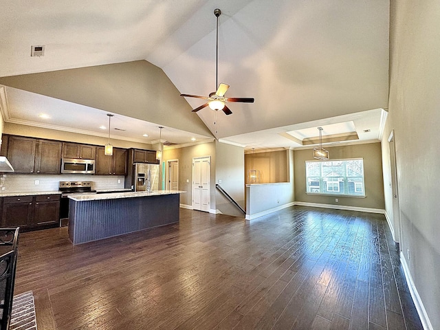 kitchen featuring dark hardwood / wood-style flooring, backsplash, stainless steel appliances, a center island with sink, and hanging light fixtures