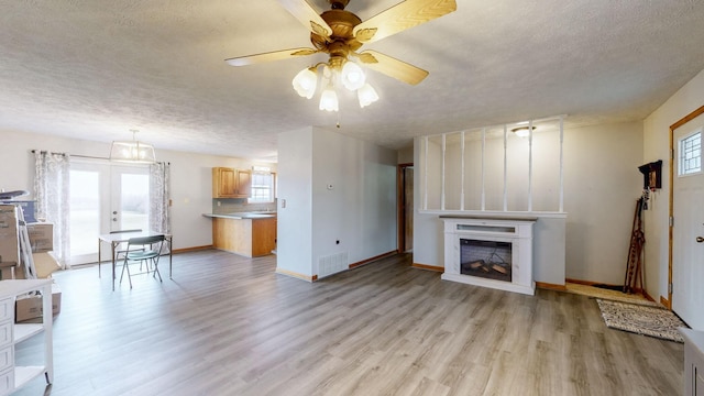 unfurnished living room with ceiling fan, a healthy amount of sunlight, and a textured ceiling