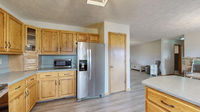 kitchen with light hardwood / wood-style floors, a textured ceiling, and appliances with stainless steel finishes