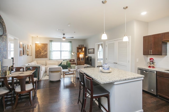 kitchen with dishwasher, light stone counters, hanging light fixtures, and a breakfast bar