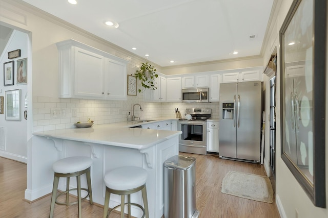 kitchen with white cabinets, sink, kitchen peninsula, and stainless steel appliances