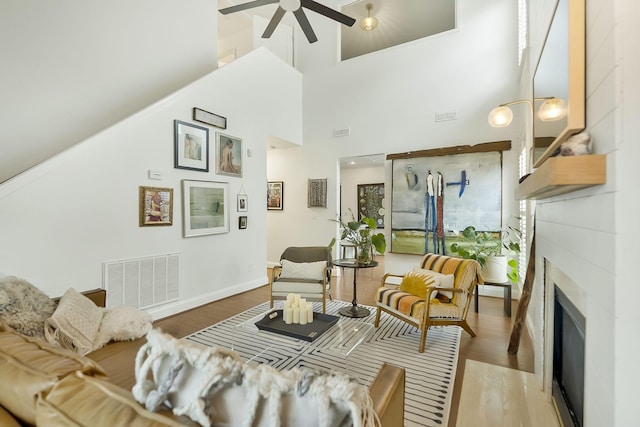 living room featuring ceiling fan, a towering ceiling, and hardwood / wood-style flooring