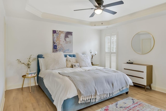 bedroom with hardwood / wood-style flooring, a raised ceiling, ceiling fan, and crown molding