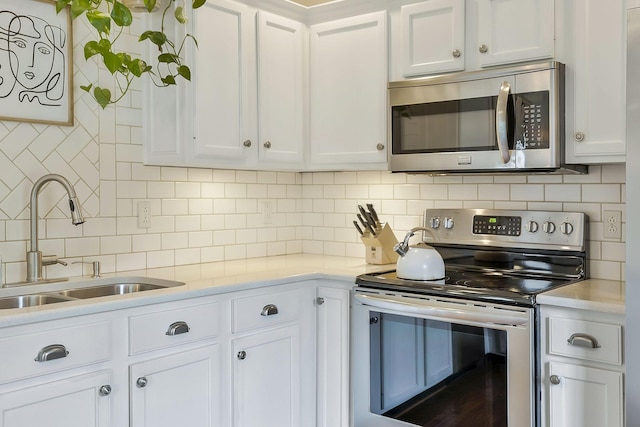 kitchen with decorative backsplash, white cabinetry, sink, and appliances with stainless steel finishes